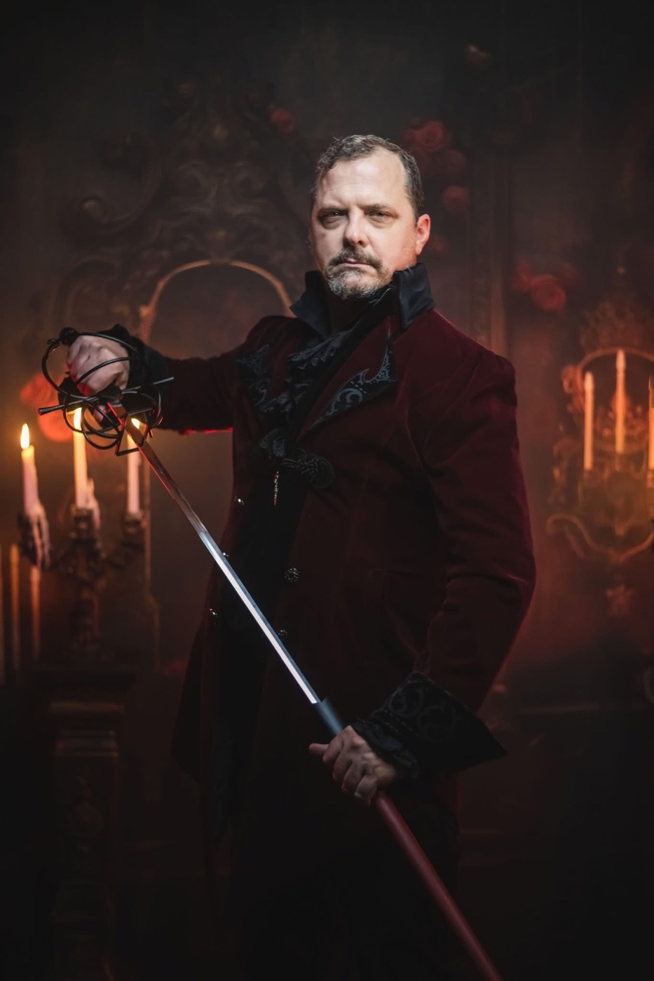Jareth in a burgundy velvet coat, holding a sword by candlelight